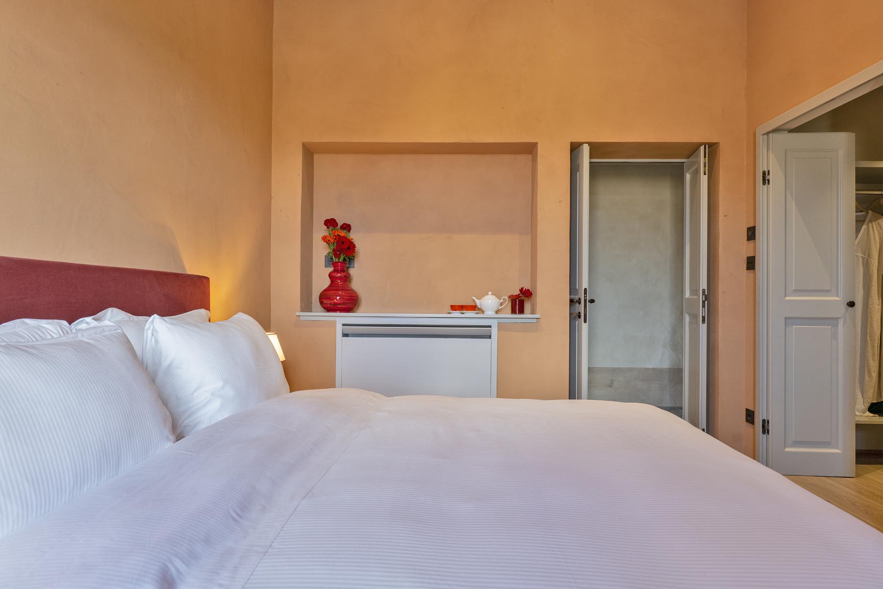 Il letto con testiera color siena e la nicchia con i fiori
