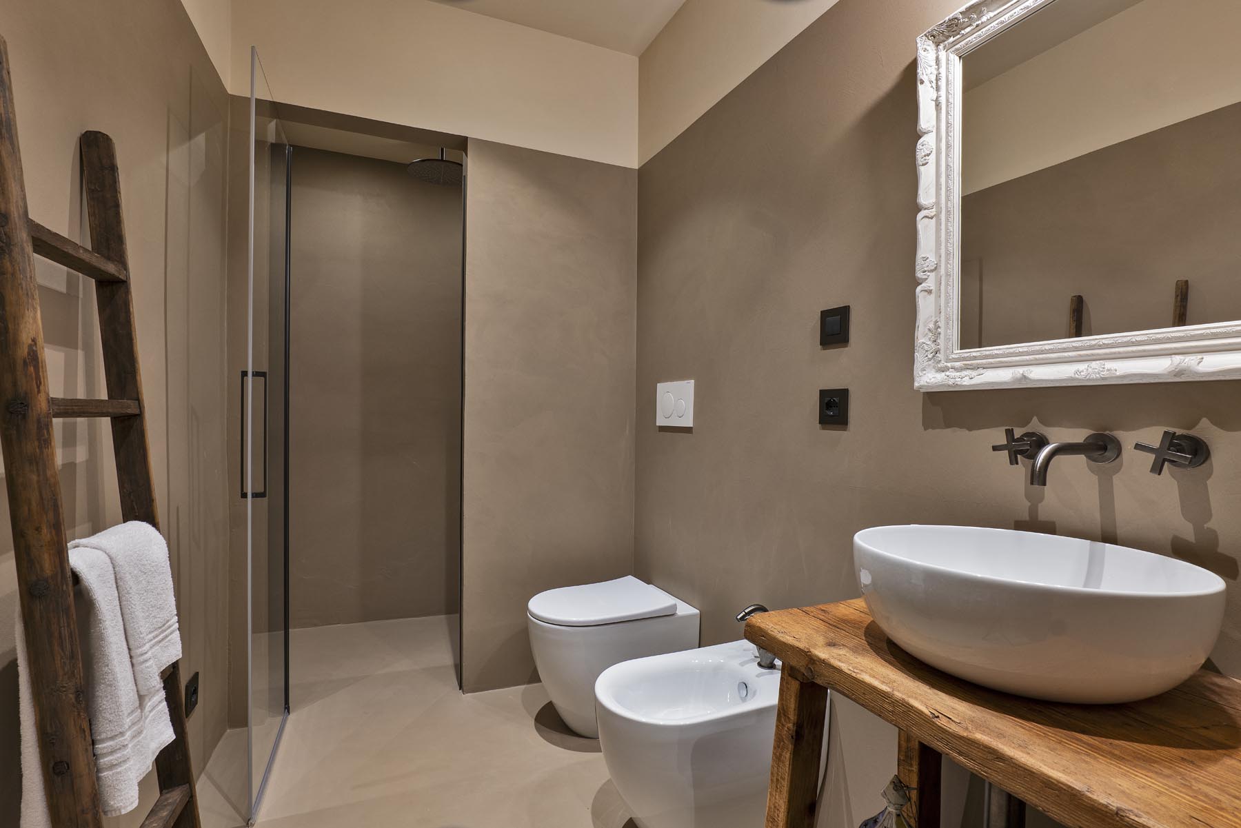 Il bagno con doccia, lavabo in ceramica e scala portasciugamani