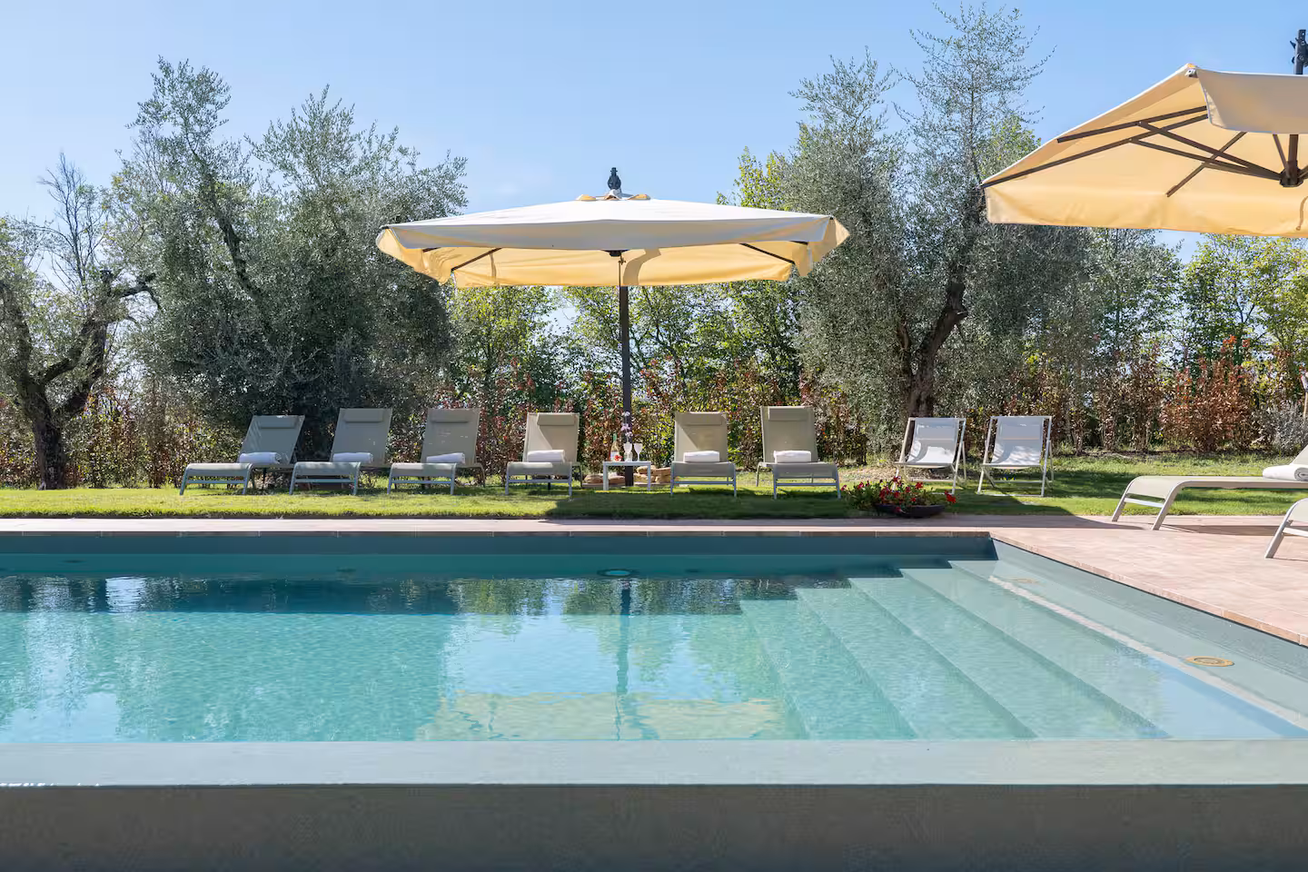 La piscina a sfioro con lettini e ombrelloni