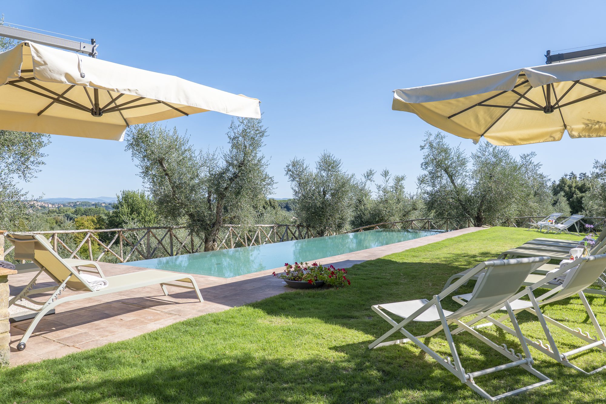 La piscina a sfioro con gli ombrelloni e la vista verso Siena